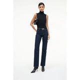 Woman wearing a black sleeveless top and dark blue jeans on a white background