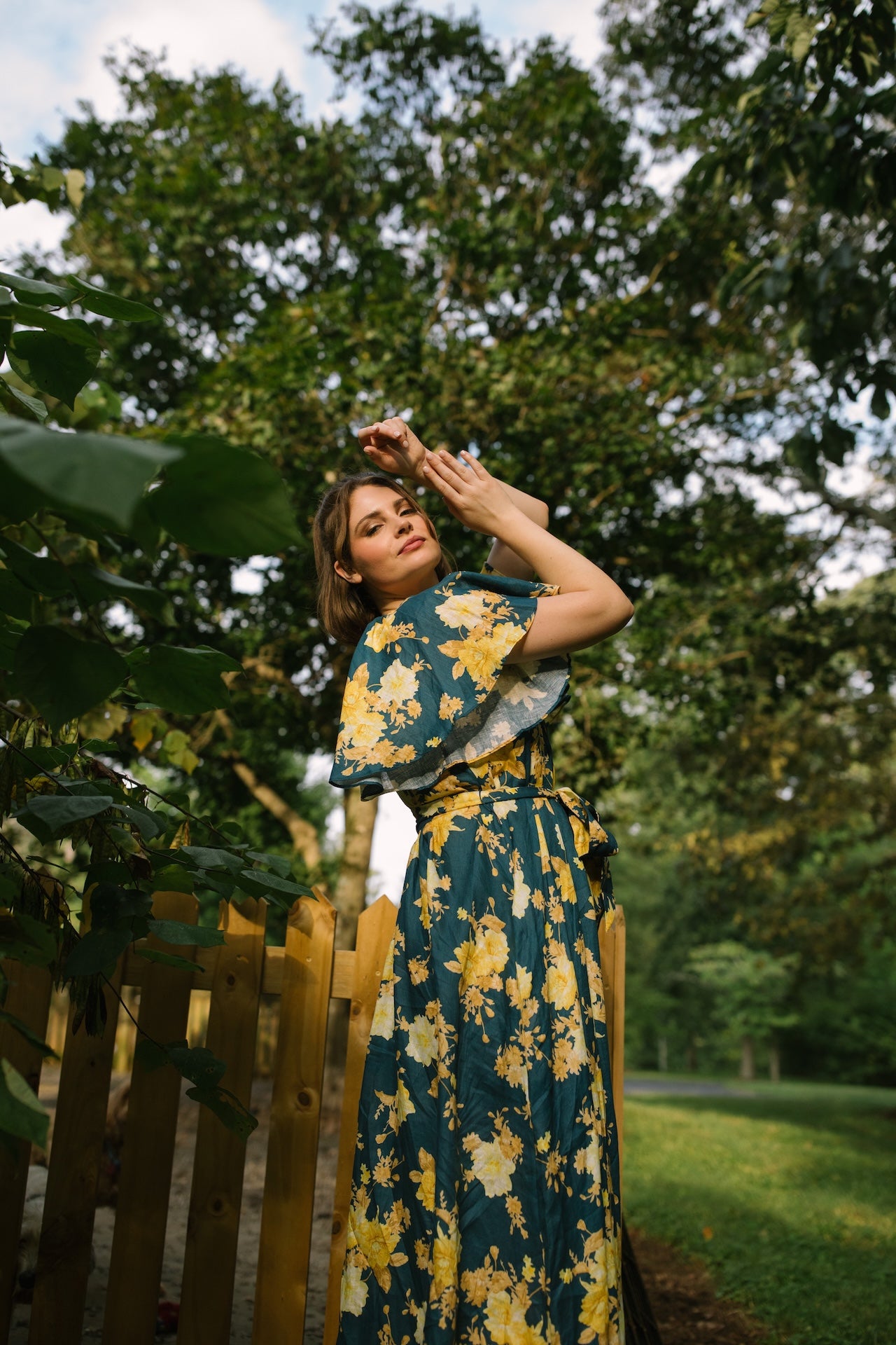 Woman in a floral dress standing outdoors with trees in the background