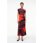 Model wearing a one-shoulder dress with red and black pattern on a white background