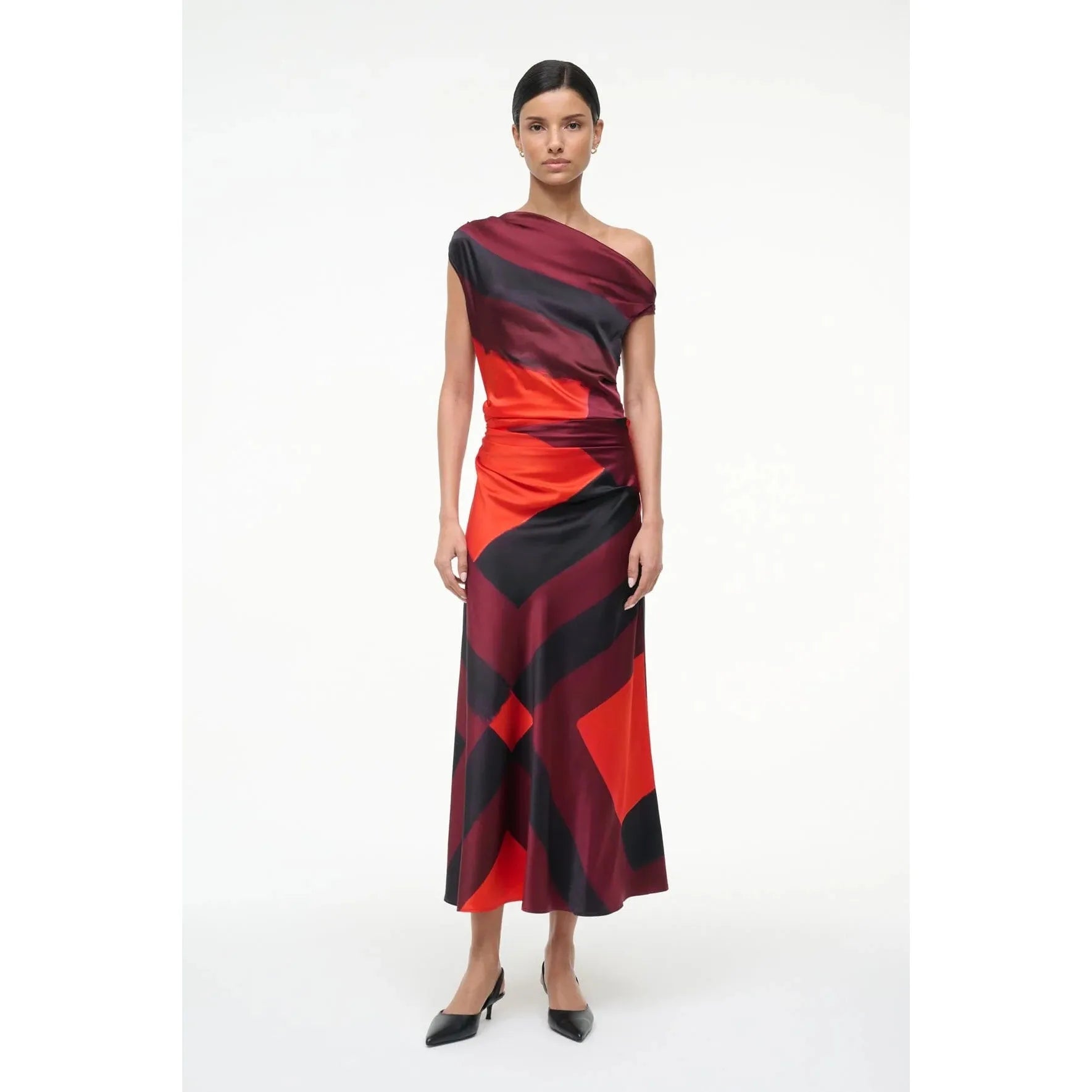 Model wearing a one-shoulder dress with red and black pattern on a white background