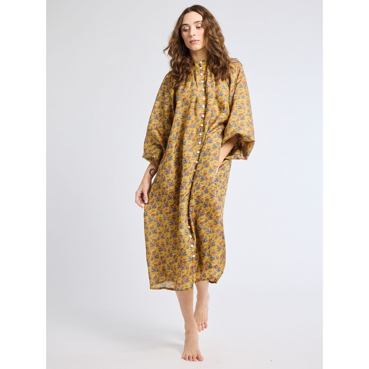Woman wearing a yellow floral dress on a white background