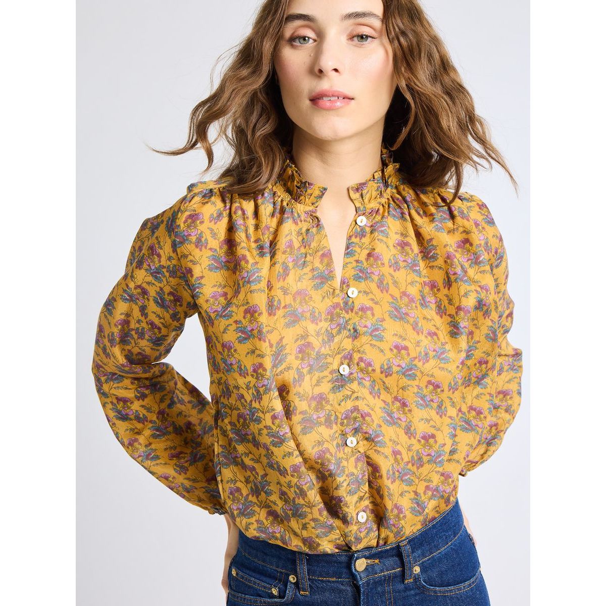 Woman wearing a yellow floral blouse against a white background