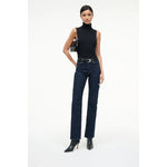Woman wearing a black sleeveless top and dark blue jeans on a white background