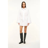 Person wearing a white dress and black boots on a white background