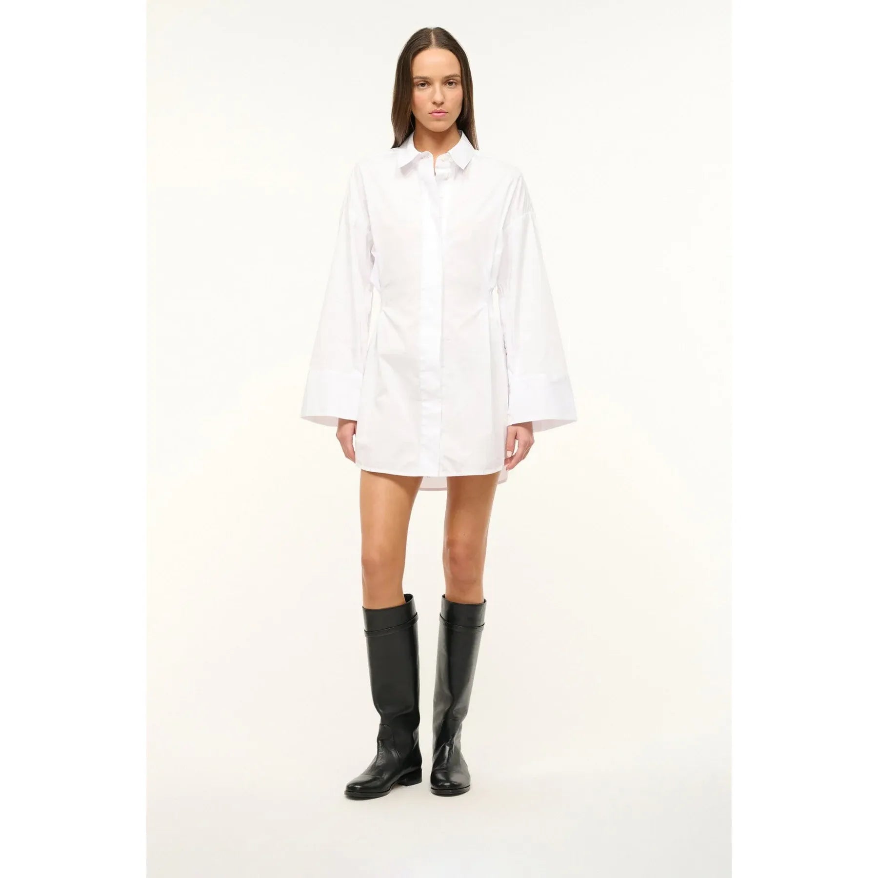 Person wearing a white dress and black boots on a white background