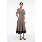 Woman wearing a brown dress with black hem on a white background