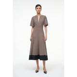 Woman wearing a brown dress with a black hem on a white background