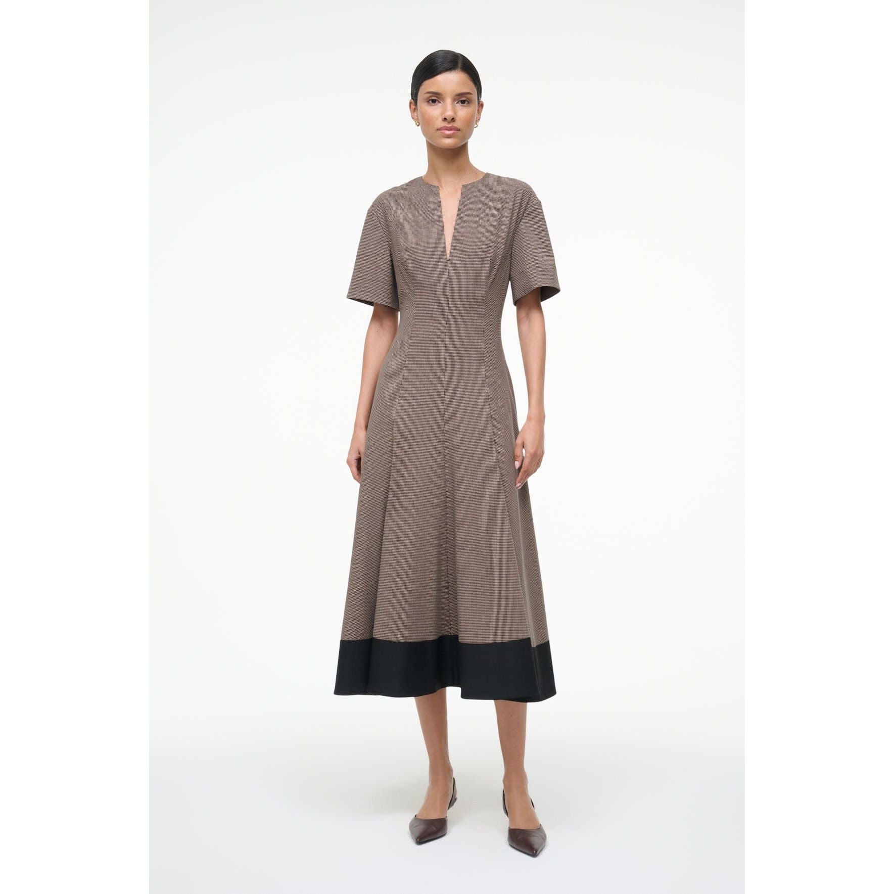 Woman wearing a brown dress with a black hem on a white background