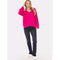 A person with long blond hair is wearing the Brodie Cashmere Saddle Shoulder Rib Knit in fuschia from Brodie Cashmere, paired with black jeans and white sneakers. They are standing against a plain white background with one hand touching their head.