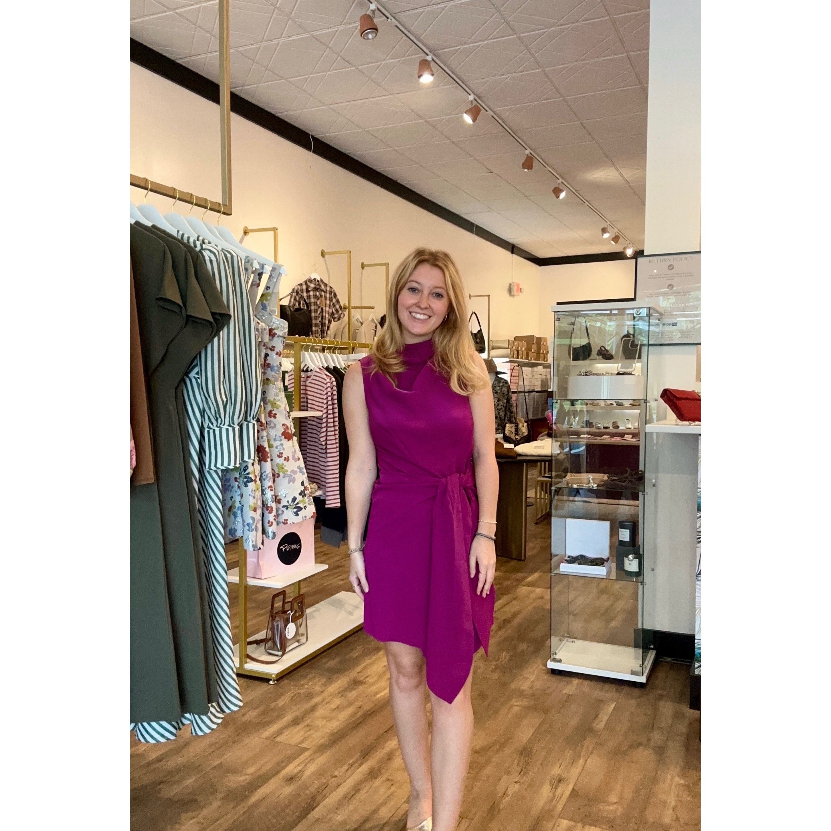 Woman in a purple dress standing in a clothing store.