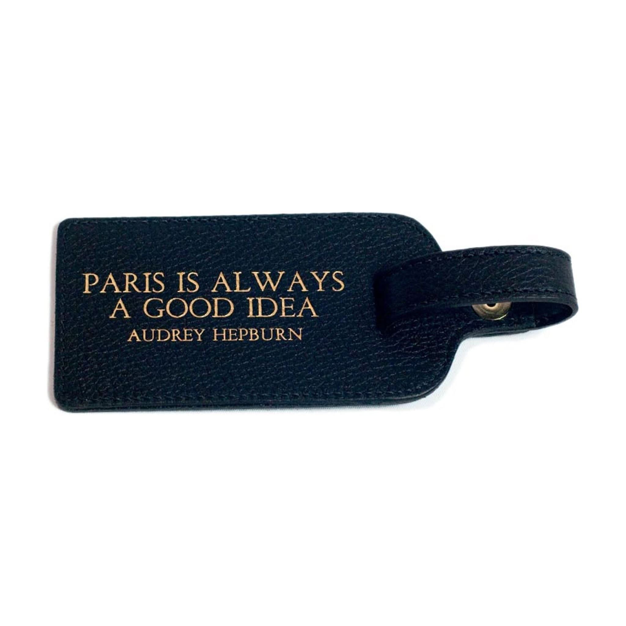 A black leather luggage tag from Kempton & Co features the gold text, "Paris is always a good idea - Audrey Hepburn.