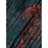 Close-up of the Rachel Comey Sisu Dress, showcasing crinkled teal fabric adorned with red abstract patterns. The rough and pleated texture adds a dynamic and tactile quality, perfectly evoking the essence of this maxi-length dress from Rachel Comey.
