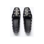 A pair of Freda Salvador's Jessie Ballet Flats, handcrafted in black, featuring a square toe and embellished with silver studs on the top and sides, set against a light gray background.