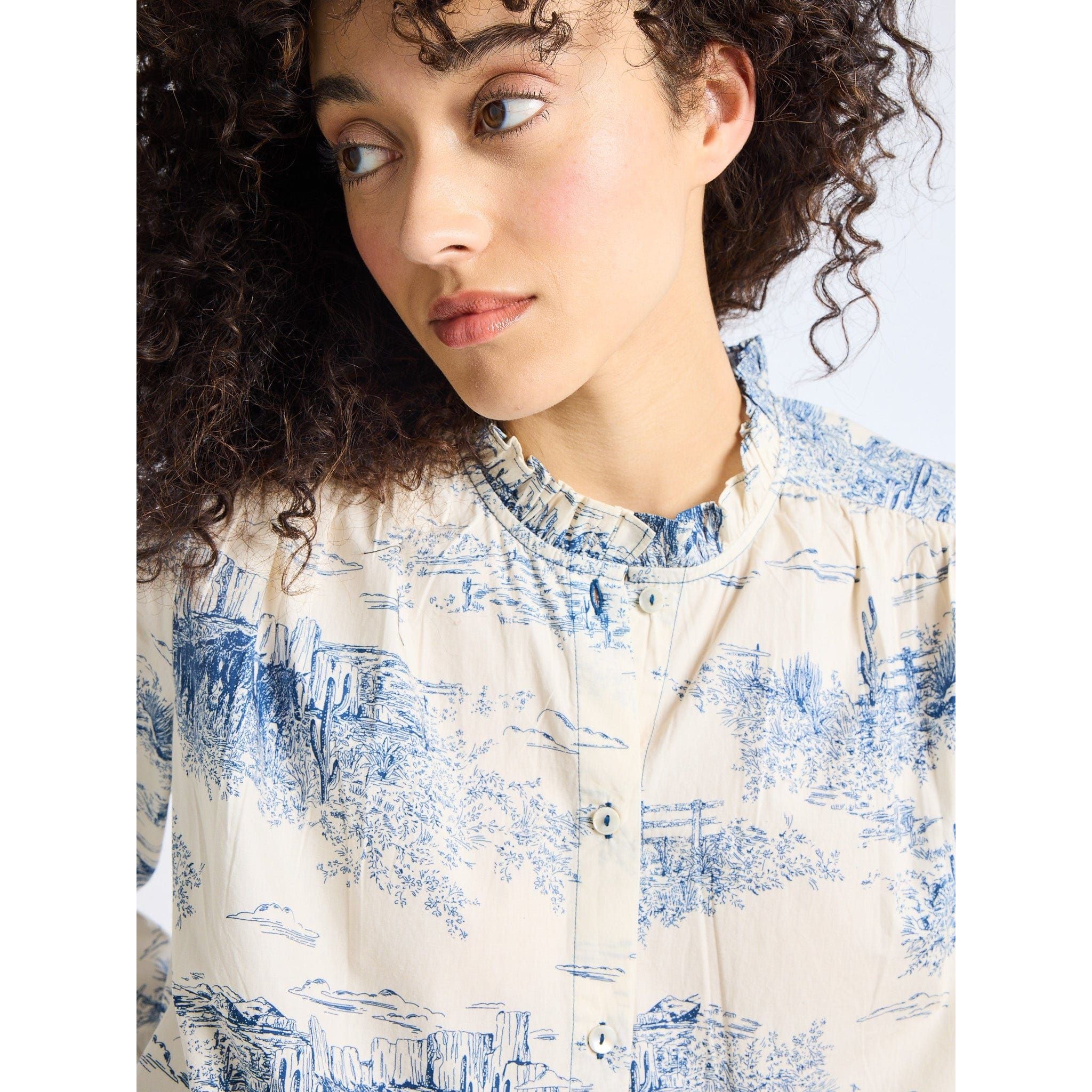 Woman wearing a blue and white patterned shirt against a light background
